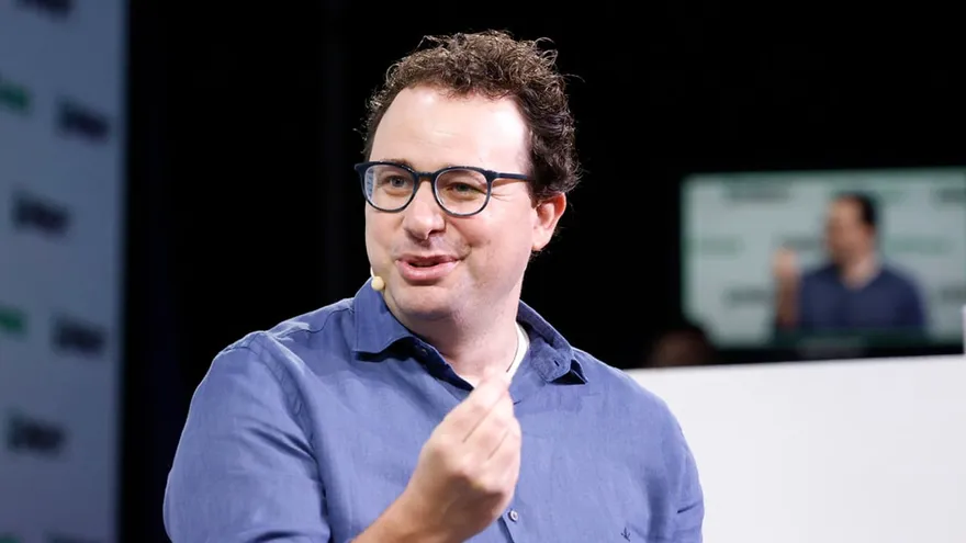 Dario Amodei, in glasses and a blue shirt, gestures while speaking on stage.