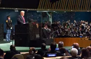 Donald Trump stands at the green marble podium of the UN General Assembly hall, with delegates seated in front of him.