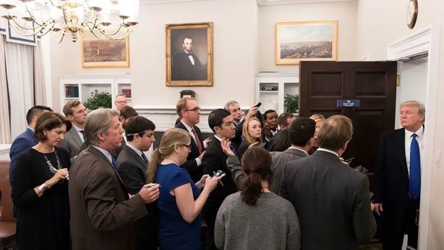 Donald Trump stands in a White House office doorway facing a group of reporters.