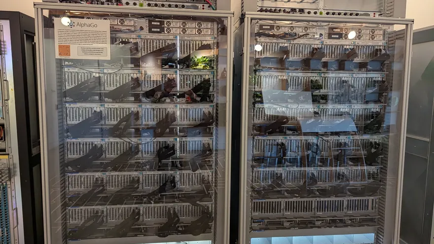 Two tall glass-fronted cabinets packed with computer hardware, with a small AlphaGo sign on the left cabinet.