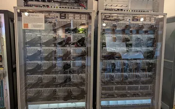 Two tall glass-fronted cabinets packed with computer hardware, with a small AlphaGo sign on the left cabinet.
